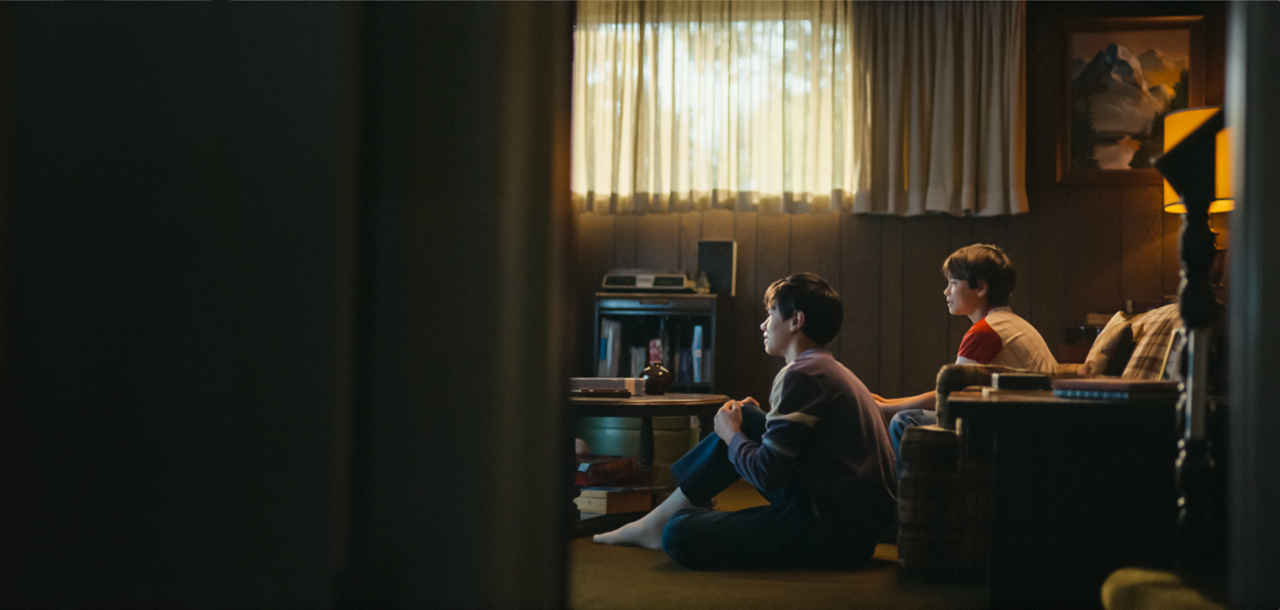 O imagine în retrospectivă cu tinerii frați McKeever urmărind atenți o emisiune TV, acasă în sufragerie.